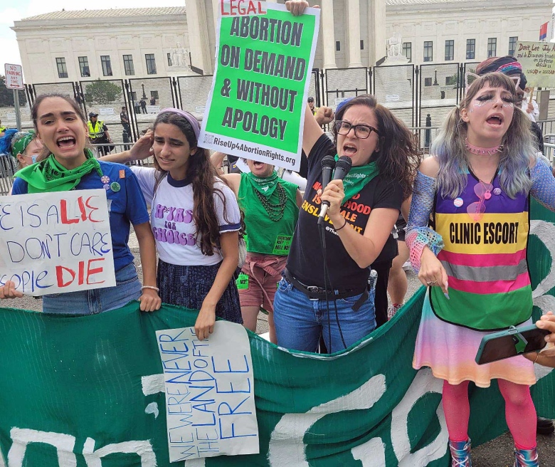 Women protest on a street, waving pro-choice signs.