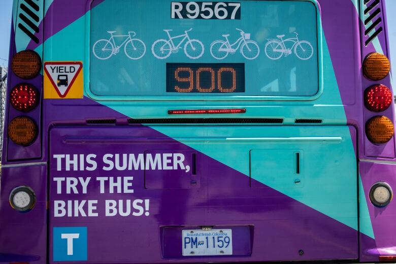 The back of a purple and blue bus, numbered 900. Bold text reads 'This summer, try the bike bus!' Clip art of bicycles are seen above the bus number.