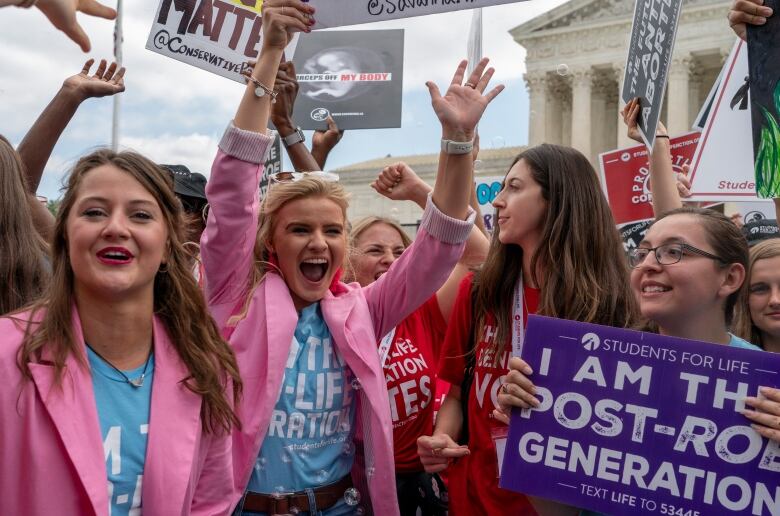 Group of demonstrators holding posters with anti-abortion messages.