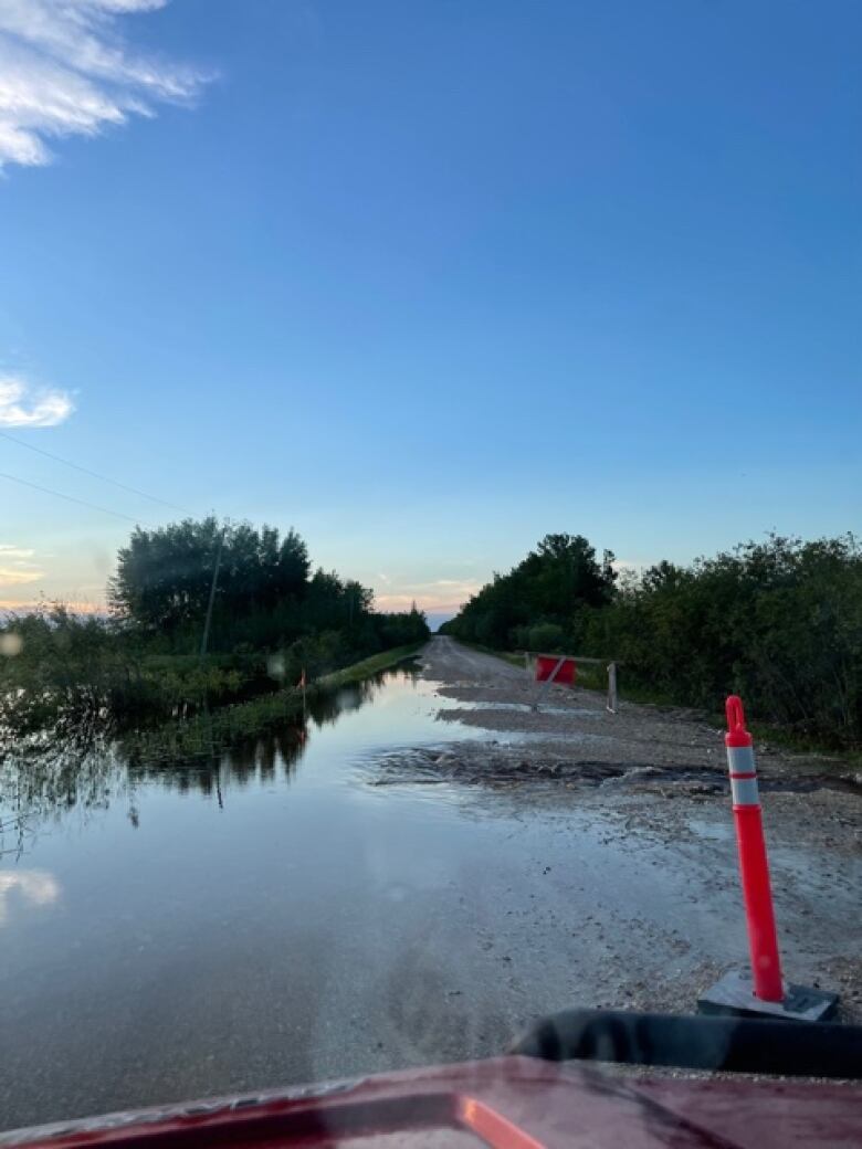 A gravel road is partly covered with water.