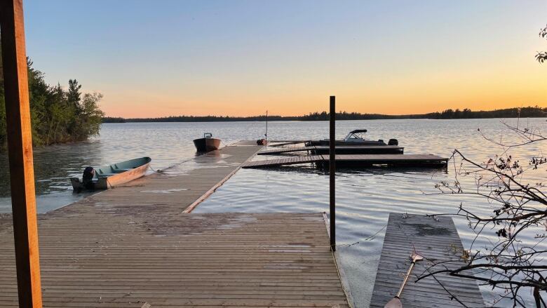 Dock on a lake is partially submerged in water with sunset in the background.