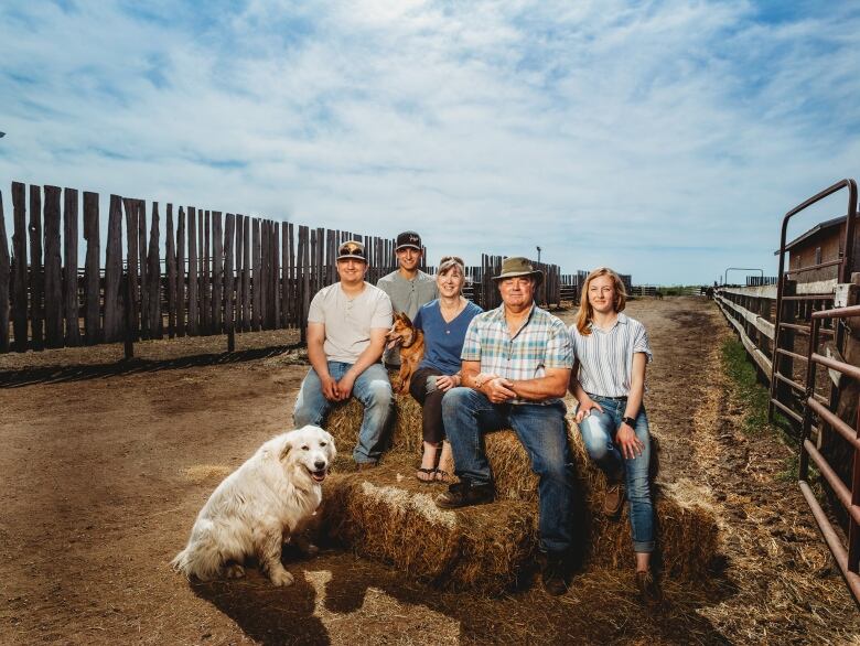 Five people sit on bales of hay.