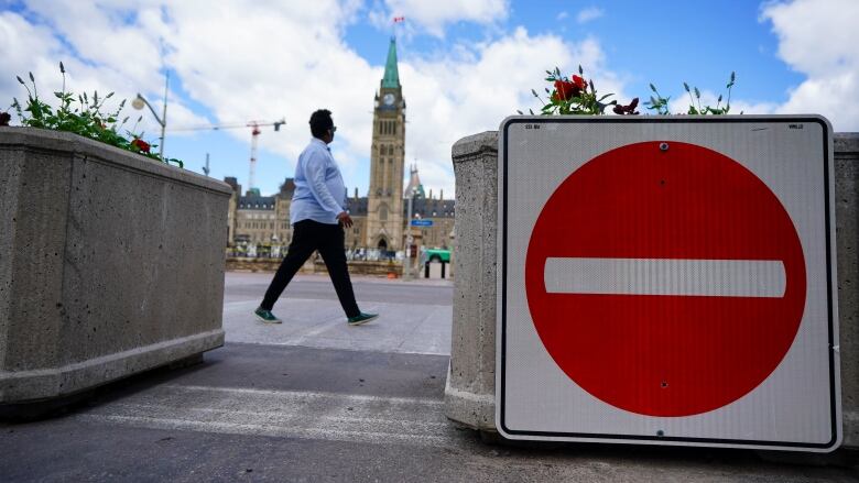 Someone passes by a road closure sign in front of Parliament Hill.