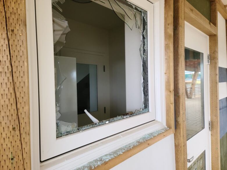 A window frame from the outside of a building, with jagged, broken glass.