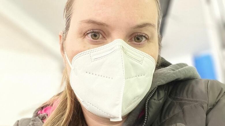 A woman wearing a face mask looks into the camera.