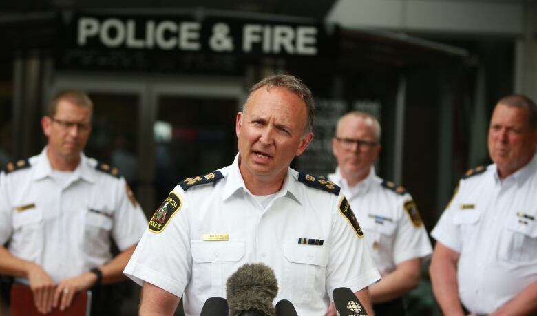 A police chief speaks at a podium with other police officers behind him.