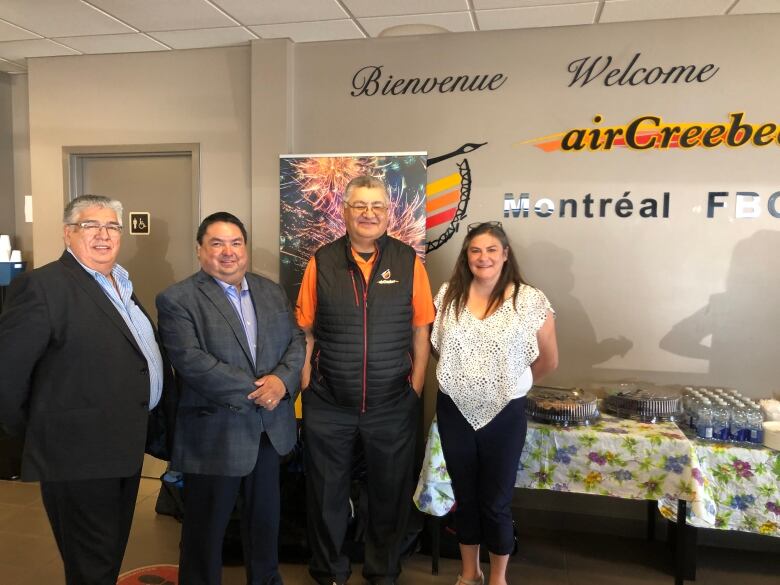 Several leaders of a Cree-owned airline stand facing the camera with the company logo on the wall behind.