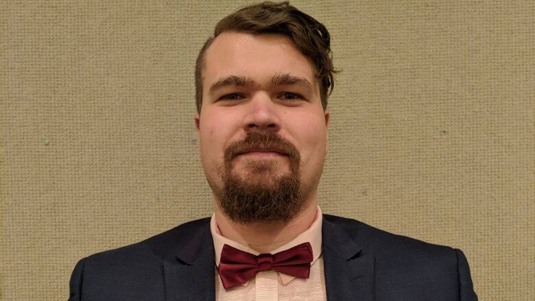 Close-up of a man with a neat beard and goatee, wearing a suit and bow tie.