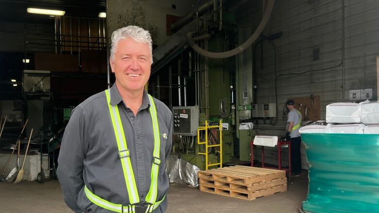 A man stands in front of a factory.