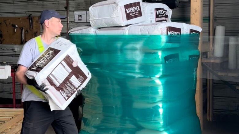 A man loads bags onto a pallet in a factory