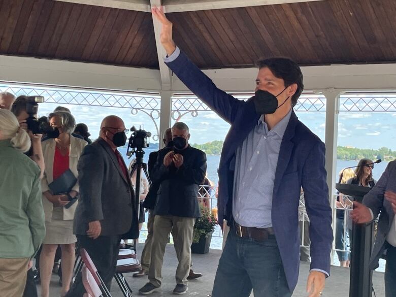 Man waves to a crowd at a gazebo.