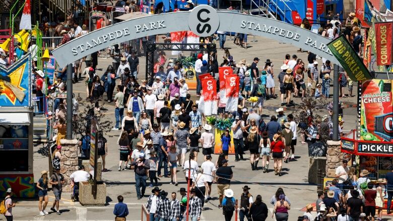 Crowds of people are walking through the Calgary Stampede front gates.