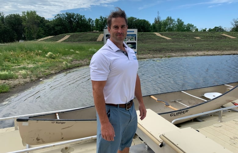 A man on a dock in front of a canoe.