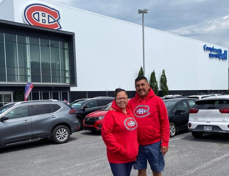 A Cree couple stands wearing red Habs logo hoodies in a parking lot outside the Brossard rink where the Montreal Canadiens hockey team practices.