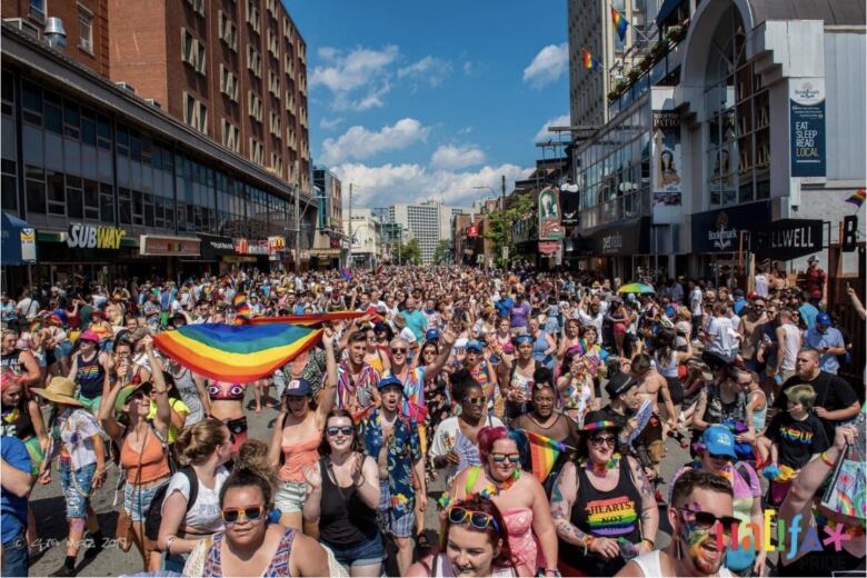 A sea of people walking in a street during a Pride parade.