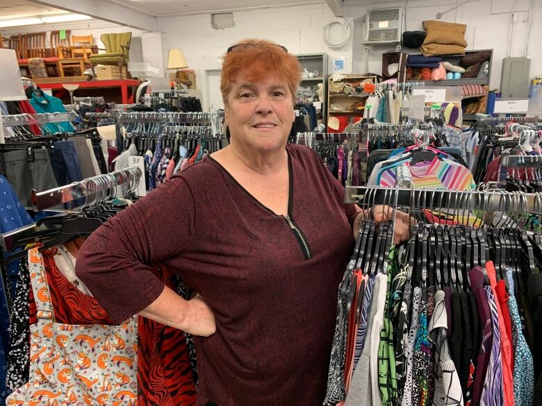 A woman stands in front of a rack of clothing