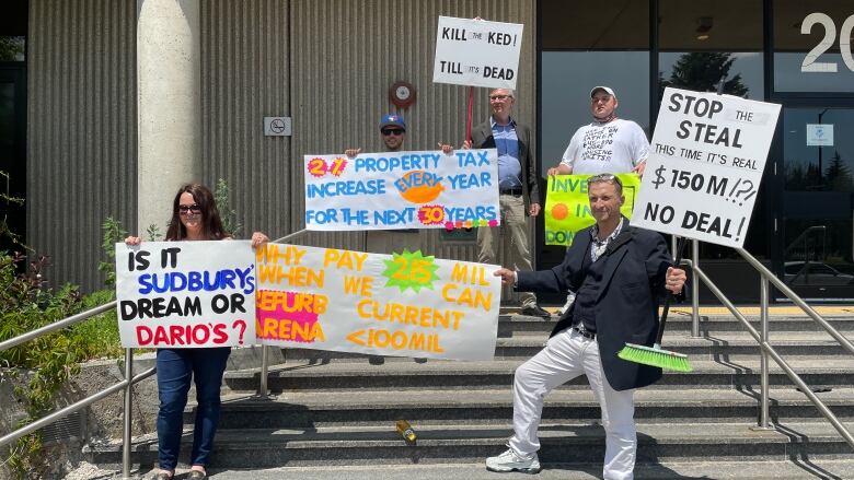 People holding protest signs on a set of outdoor stairs.