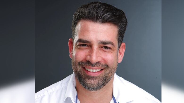 A smiling man with dark hair and a short beard is shown in a headshot.