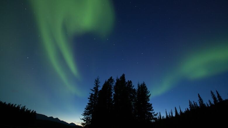 The Northern Lights are visible during a clear summer's night.