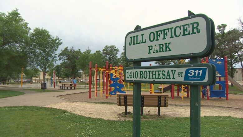 A park sign in front of a play structure.