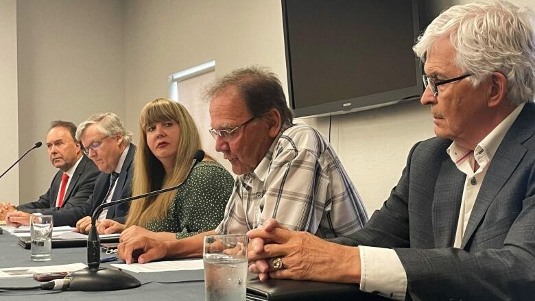 A group of five people at a table during a news conference.