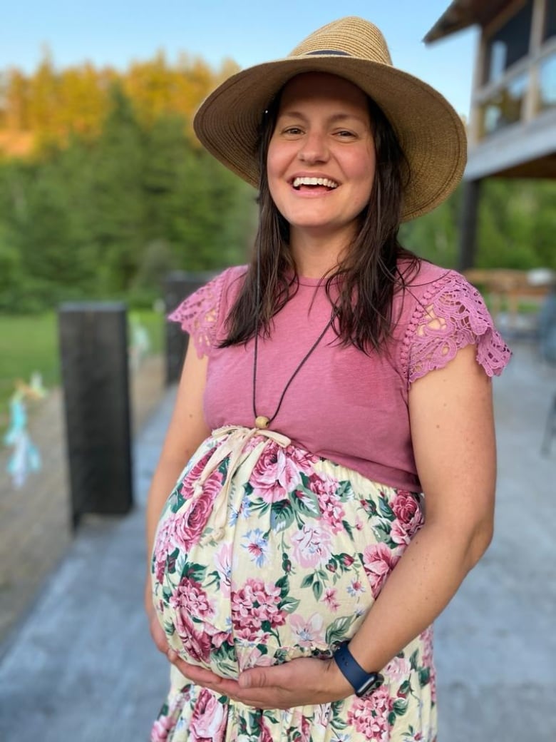 A smiling pregnant woman holding her belly.