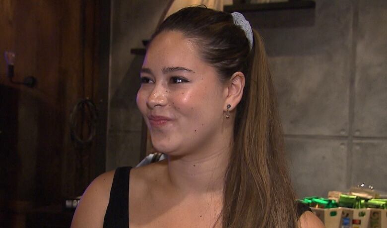 A woman in a busy restaurant speaks to someone off camera. 