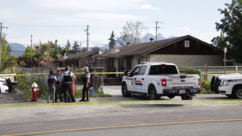 Multiple police officers stand by several RCMP cars outside a residence, as they investigate the scene of a double shooting in Maple Ridge, B.C. on Friday that saw one 35-year-old woman, Cashmere Ali, die of her injuries in hospital.