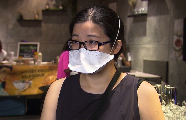 Diem Nguyen, the mother of four-year-old Minh Nguyen, stands in front of the camera wearing glasses and an N95 mask inside a Montreal restaurant.