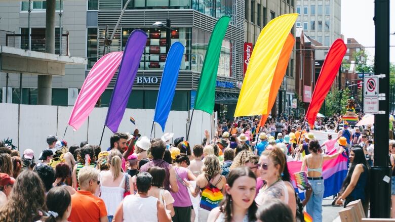 Hundreds of people in the street at a Pride parade with colourful flags