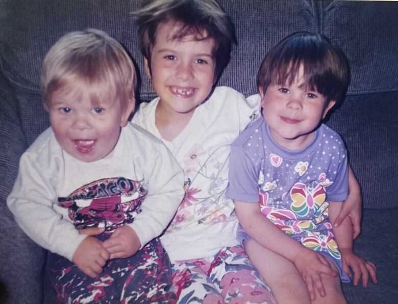 Three children sit on a couch. 