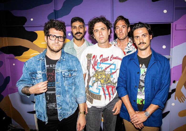 Five men pose for a photo while smiling. 