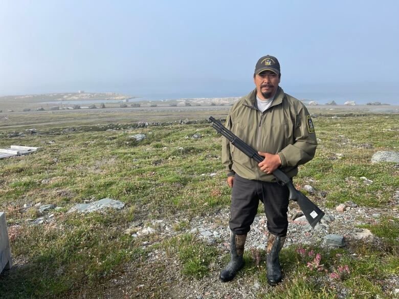 A portrait of a man outside holding a hunting gun.