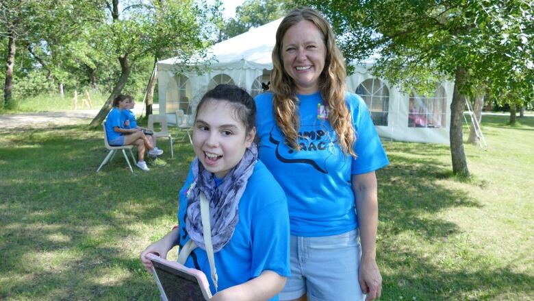 Adult and a teen holding an iPad stand together outdoors.