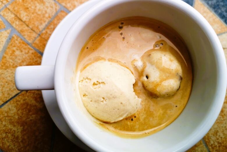 White coffee cup with coffee and a scoop of ice cream.