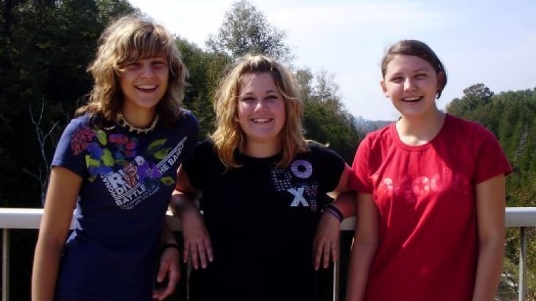 Three woman smiling in an outdoor setting.