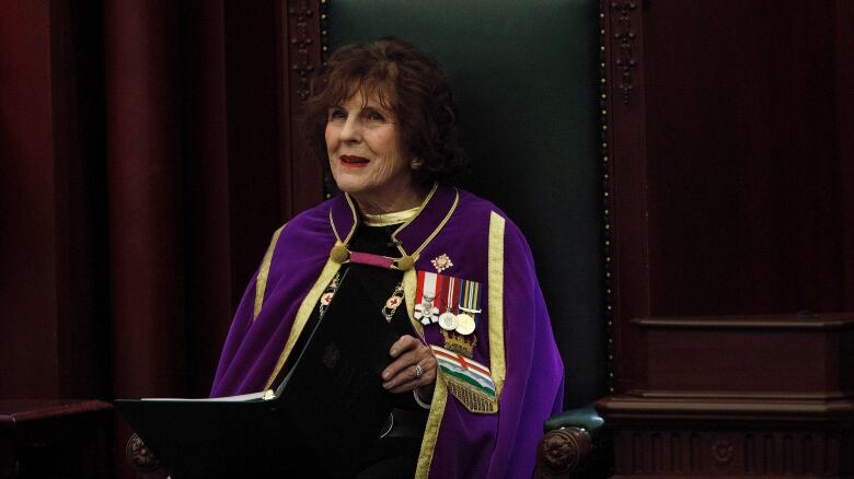 Then lieutenant-governor Lois Mitchell sits in a wooden chair in the Alberta Legislature in Edmonton as she delivers the throne speech from a black binder on March 8, 2018. 