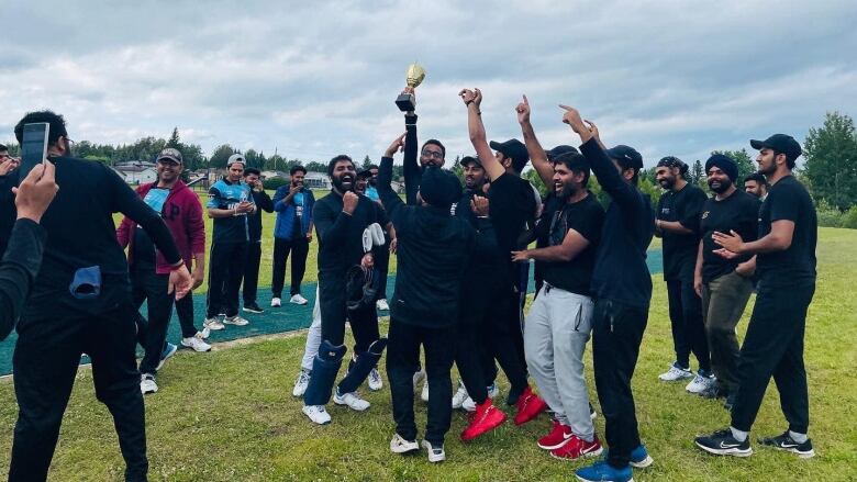 A team cheering with one player holding a trophy in their hands.