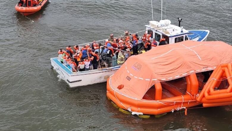 Passengers are seen wearing life-jackets after being evacuated from the MV Holiday Island.