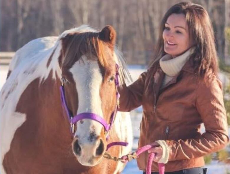 Woman poses with horse in winter.