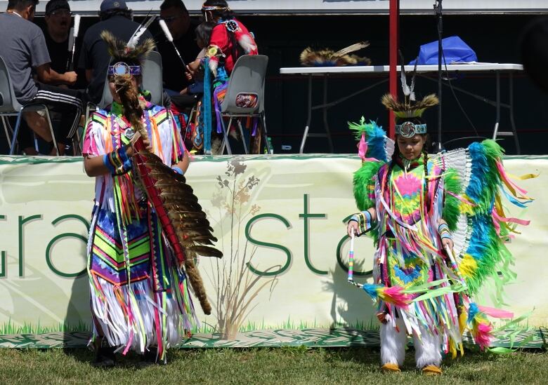 Two girls wear colourful outfits as they dance at a powwow.