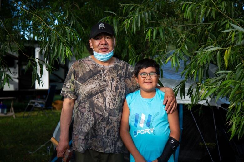 A man stands with his arm around a boy.