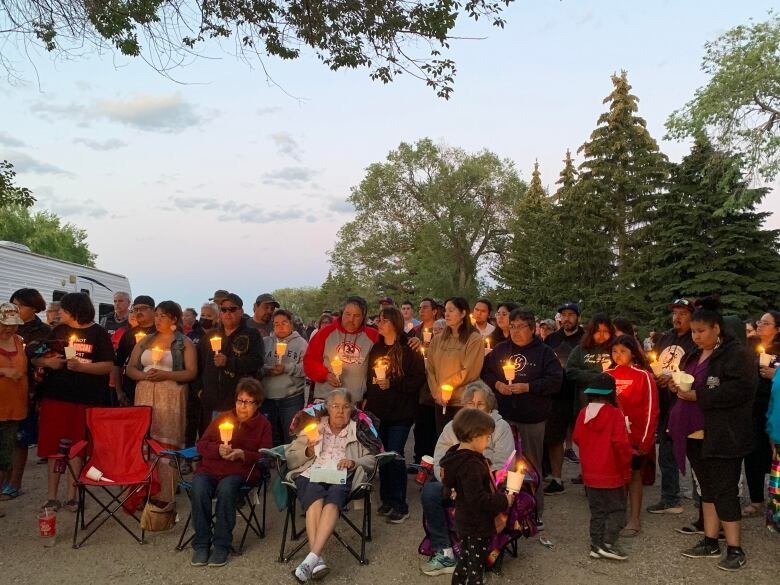 A large group of people holding candles at a vigil.