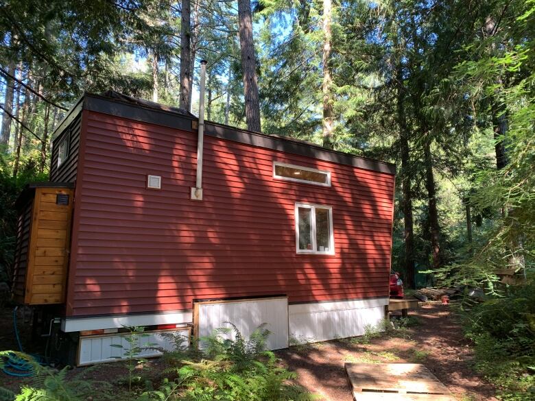 A small home located in the woods, with a red-coloured exterior.