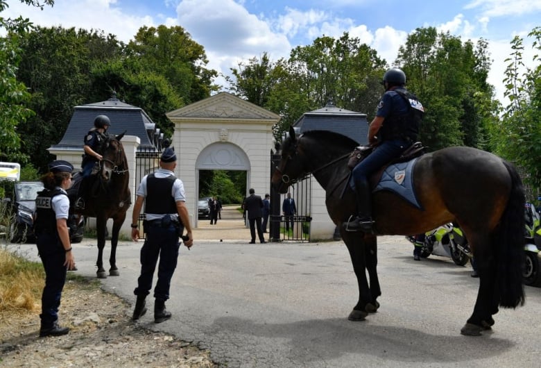 Police, some on horseback, guard a building.