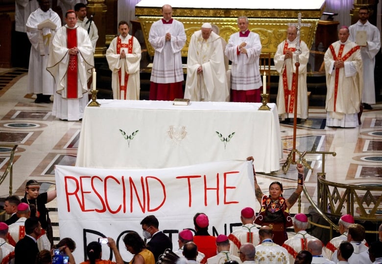 Protesters hold a banner at the front of church mass.