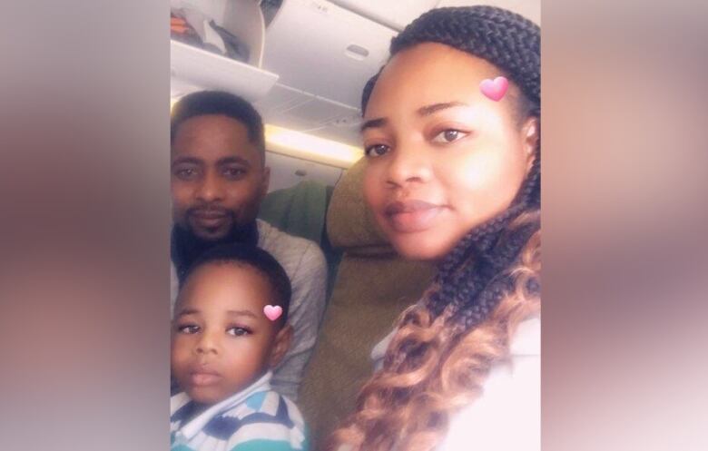 A young child sits between a man and a woman on an airplane.