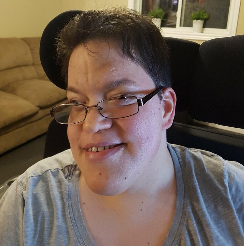 A woman sits in a wheelchair in a home. 