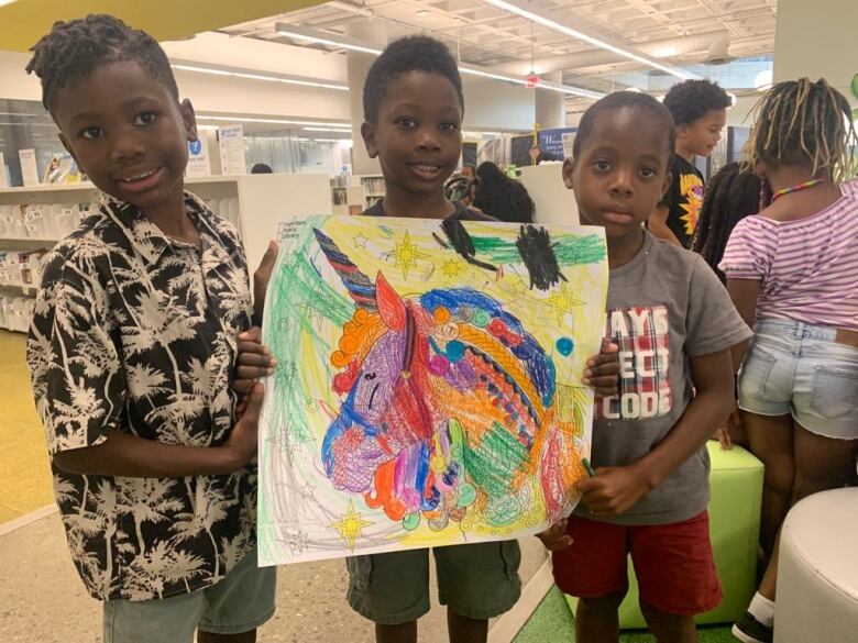 Three kids hold a drawing