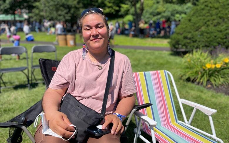 A woman smiling and sitting outside on a lawn chair.